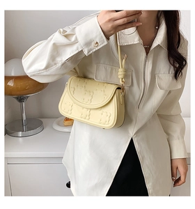 Detail of light yellow biscuit bag with embossed floral texture and gold hardware