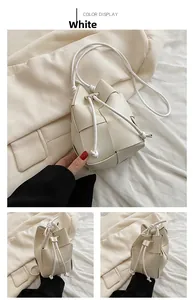 Detail of white woven bucket bag with drawstring closure and leather shoulder strap