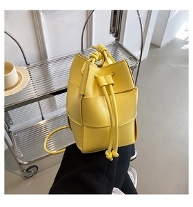 Close-up detail of yellow woven leather bucket bag featuring signature large grid pattern