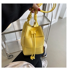 Close-up of bright yellow woven bucket bag with thick Intrecciato texture and drawstring