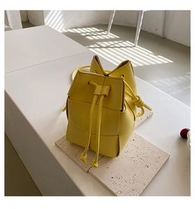Detailed close-up of woven leather bucket bag texture and knot drawstring closure