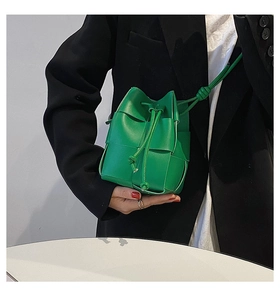 Close-up of emerald green hand-woven leather bucket bag with drawstring closure detail