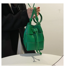 Detail of green hand-woven leather bucket bag showing Intrecciato weave and texture
