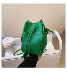 Detail of green woven texture bucket bag with drawstring closure on a display cart