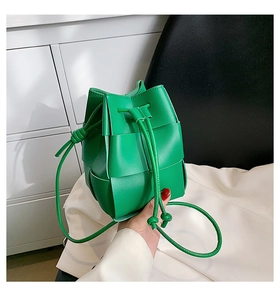 Detailed close-up of bright green hand-woven leather bucket bag with drawstring closure