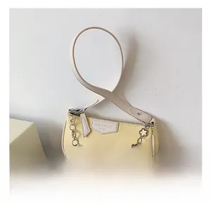 Détail du sac à main jaune clair avec chaîne florale argentée et étiquette de marque