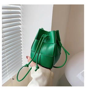 Detail of green woven leather bucket bag with chunky square pattern and drawstring closure