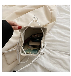 Interior capacity detail of the white woven bucket bag holding phone and cosmetics