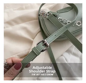 Détail de la boucle réglable et de la chaîne en métal sur le sac à bandoulière vert