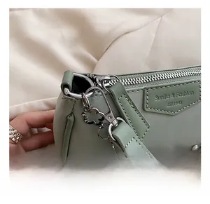 Gros plan d'un sac en similicuir vert clair avec crochet argenté et chaîne à fleurs