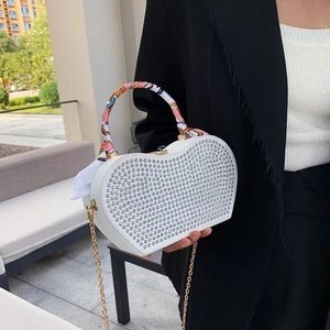 White heart-shaped rhinestone clutch bag with gold chain and silk scarf handle detail