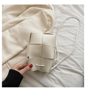 Detailed view of woven cream leather crossbody bucket bag with intricate grid pattern