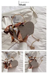 Detail of khaki heart-shaped evening bag with silver bead décor and gold ring handle