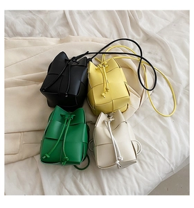 Flat lay of mini woven leather bucket bags in black, yellow, green and beige colors