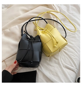 Detail view of the hand-woven bucket bag featuring a black and yellow leather texture strap