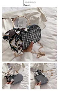 Close-up of a green heart-shaped handbag featuring silver rivets and golden ring handle