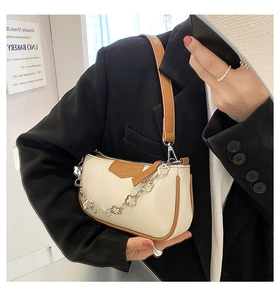 Détail du sac baguette crème avec chaîne fleur argentée et bandoulière marron contrastée