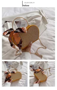 Detail of yellow heart-shaped bag with rhinestones, metal handle and silk scarf