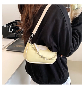 Détail du sac demi-lune jaune pâle avec chaîne florale en métal et écusson logo