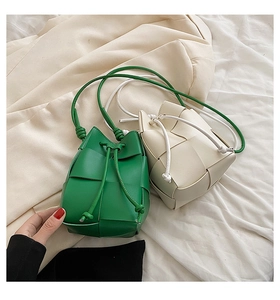 Detail showing handwoven bucket bags in green and white with intricate wide-grid weave