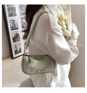 Détail du sac sous le bras en cuir vert clair avec chaîne décorative en fleur de prunier