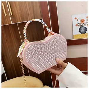 Detailed view of pink heart-shaped bag with silver studs and silk scarf handle detail