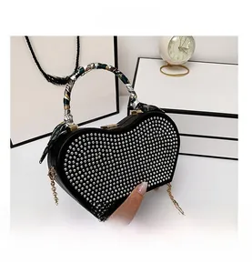 Detail of black heart-shaped evening bag with silver rhinestones and silk scarf handle