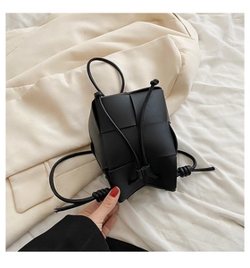 Detail of hand-woven black leather bucket bag with wide intrecciato pattern and drawstring