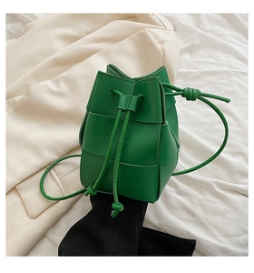 Detail of bright green woven leather bucket bag with drawstring closure and knotted straps
