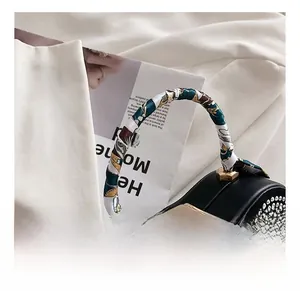 Detail of black rhinestone handbag featuring silk scarf wrapped handle and gold lock
