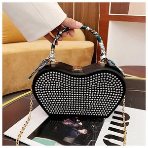 Detail of heart-shaped handbag with silver studs and silk scarf wrapped metal handle