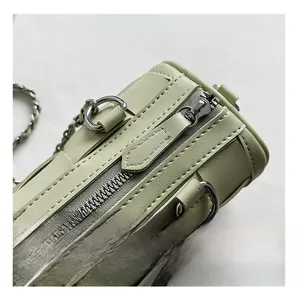 Detail view of smooth silver zipper and fine stitching on a mint green cylinder bag