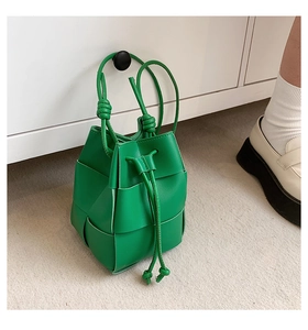 Detail of green woven leather bucket bag featuring wide Intrecciato craftsmanship
