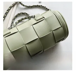 Detail of light green woven cylinder bag showing leather texture and chunky chain strap