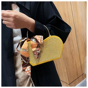 Detail of yellow heart-shaped bag with silver studs, metal ring handle and floral scarf