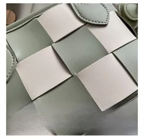 Vue macro du motif en damier tissé vert sauge et crème sur le sac seau en cuir