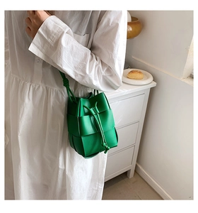Close-up of green woven leather bucket bag with drawstring closure and knotted strap