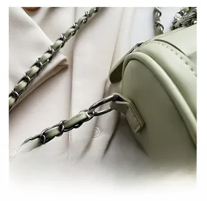 Detail of silver chain strap buckle and precise stitching on mint green cylinder bag