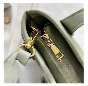 Détail de la fermeture éclair dorée et de l'anneau en D sur un sac seau vert clair