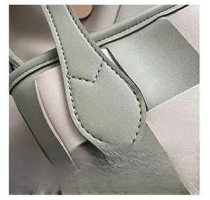 Détail macro des coutures en V sur le sac seau tissé en vert sauge et beige