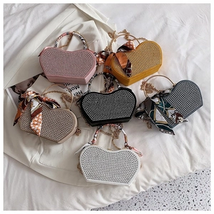 Detail of heart-shaped handbag collection with metal rivets and silk scarf handle decor