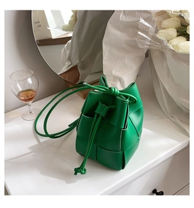 Detail of green wide-woven bucket bag with drawstring strap on elegant table set