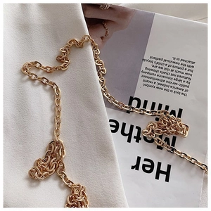 Detail shot of a thick golden oval link chain necklace on a white textured background