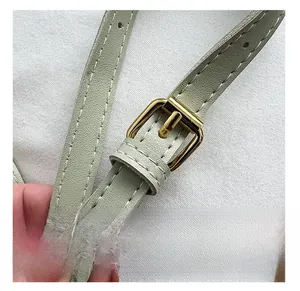 Détail de la bandoulière en cuir vert clair avec boucle dorée et coutures renforcées