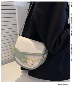 Detail of green and white saddle bag with crocodile texture and gold chain on model