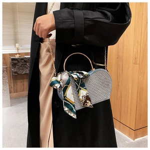 Detail of blue heart-shaped rivet bag with golden handle and silk scarf accessory