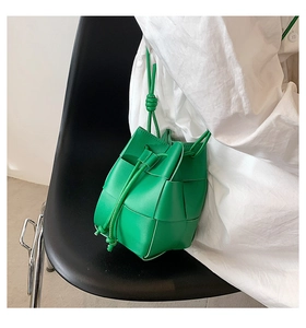 Detail of lime green woven bucket bag with drawstring closure on a black chair