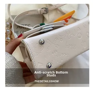 Macro view of white embossed leather bag with protective metal feet and star patterns