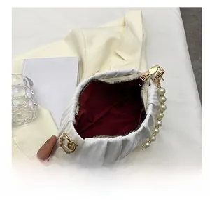 Détail du sac plissé blanc avec anse en grosses perles et doublure intérieure rouge
