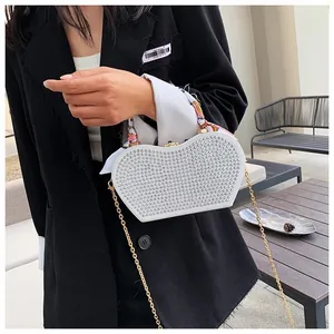 Close-up of white heart-shaped rhinestone evening bag with chain and printed silk handle